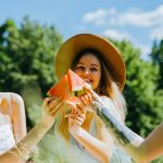 Three friends sharing watermelon on a sunny day, celebrating friendship outdoors.